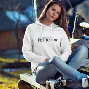 Una mujer sentada en un columpio lleva una sudadera con capucha y jeans, con una expresión pensativa.